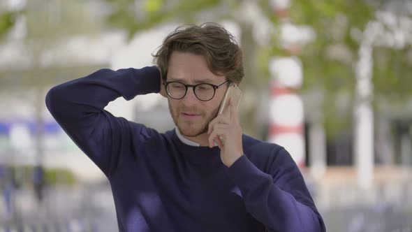 Doubtful Man Talking By Smartphone Outdoor alt