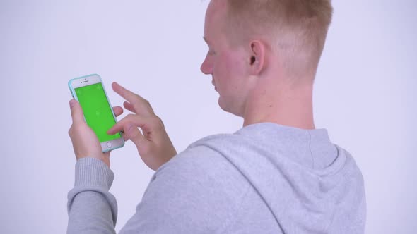 Rear View of Young Blonde Man Using Phone alt