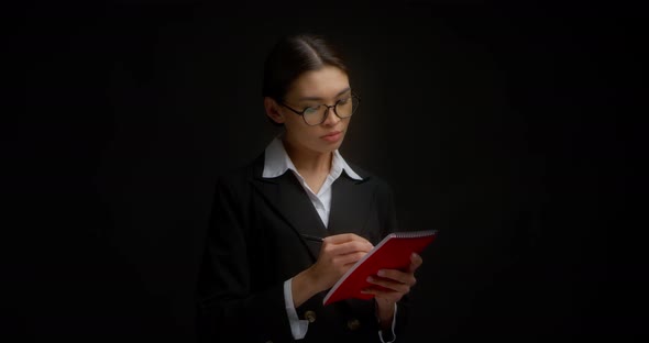 Business Woman Confidently Writes in a Red Notebook and Puts Her Signature