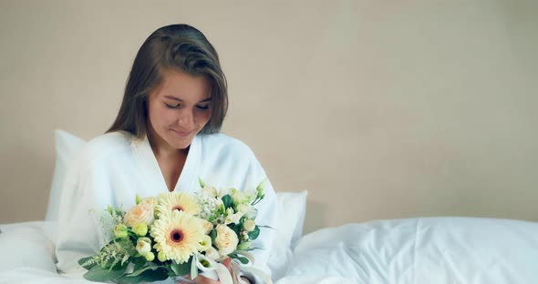 Happy Lady Holds Fresh Flowers Bouquet Sitting on Bed