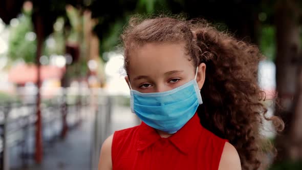 Child a Little Girl 78 Years Old Stands on the Street Wearing Protective Masks Against the Covid19 alt