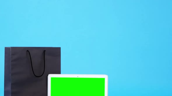 Shopping bag, disposable coffee cup and laptop on blue background alt