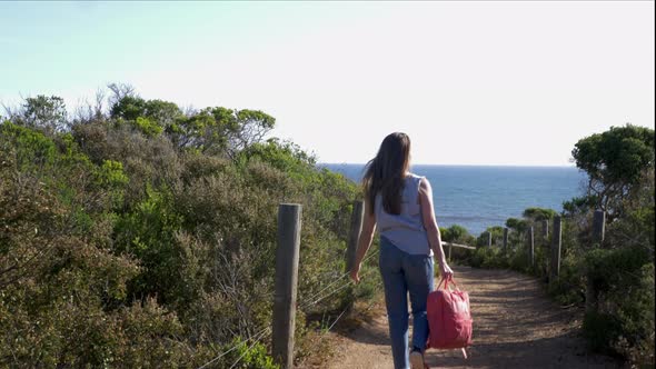 Rear view of young woman walking towards sea, Victoria , Australia