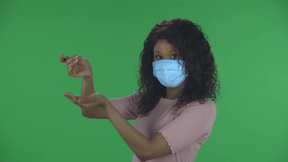 Portrait of Beautiful African American Young Woman in Medical Protective Face Mask Pours Medicine alt