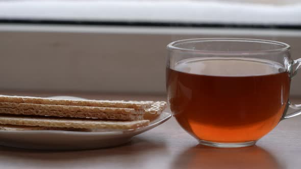 A Large Mug of Tea and Diet Bread in a Plate on the Windowsill in Winter