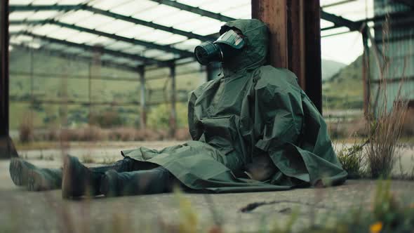 Man with Gas Mask Sitting on a Beam in a War Bombed Building alt