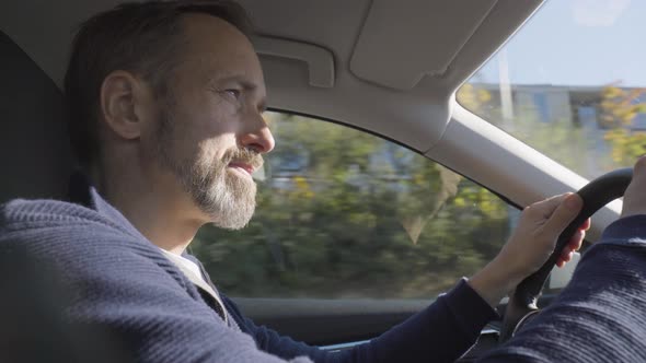 A Middleaged Handsome Caucasian Man Looks Around As He Drives a Car Through an Urban Area