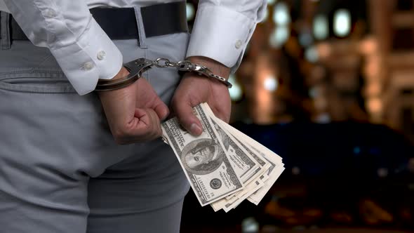 Close Up Handcuffed Man Holding Hundred Dollars. alt