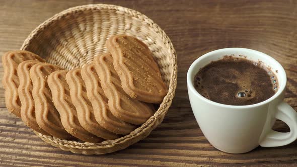 Cup of coffee with cookies on a wooden table.