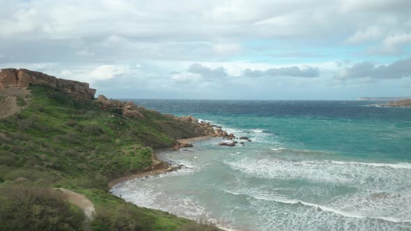 AERIAL: Panoramic View of Ghajn Tuffieha Bay and Il-Qarraba Rock on a Windy Bright Day