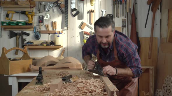 Carpenter Planes Solid Wood in his Workshop