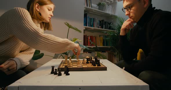 Young Friends Play Chess Game at Home at Night