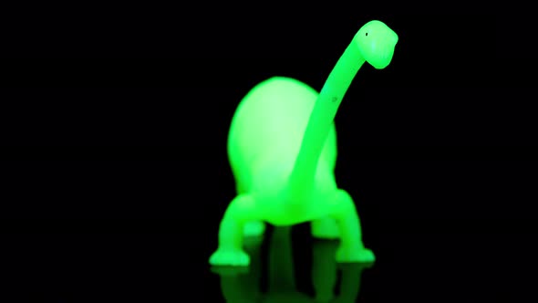 Green Toy Dinosaur Turning Agaisnt Black alt