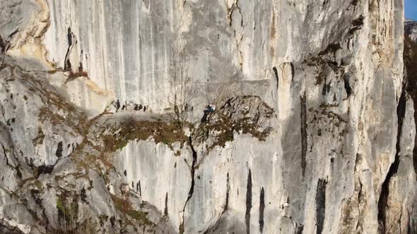 Backwards shot of a man sitting on a cliff ledge alt