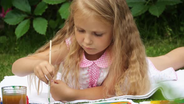 Little girl draws paints on the nature