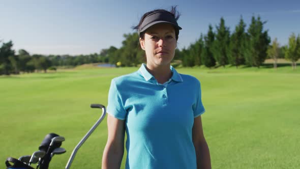 Portrait of female caucasian golf player crossing her arms while standing at golf course alt