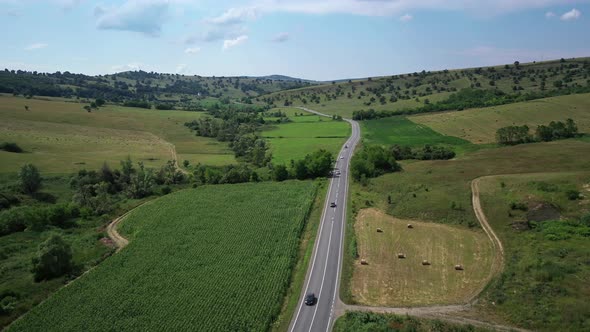 Aerial View of Cars Moving Along Highway Surrounded By Green Meadows at Sunny Summer Morning
