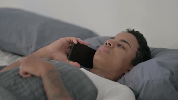 Close Up African Woman Talking on Smartphone While Laying in Bed alt