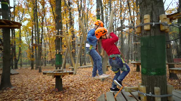 Two little girls in orange helmets in adventure park in safety equipment in autumn  day.