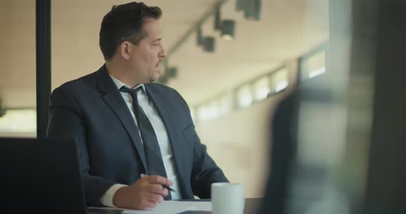 Medium shot of a businessman consulting with his partner before signing a contract during a meting alt