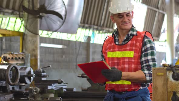 Caucasian engineer foreman writing on checklist clipboard checking on factory machine