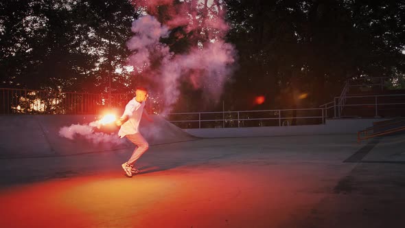 Young Guy is Holding Glowing Red Signal Flare Jumping and Spinning While Performing Breakdance on alt