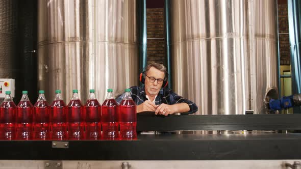 Worker checking juice bottles on production line alt