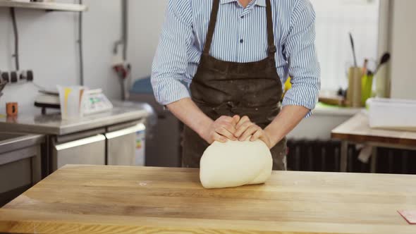 Handsome Male Baker in Black Apron Kneading Dough Making Bread at the Bakery Kithen alt