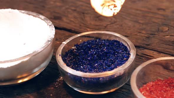Close-up of glassblower attaching colored glass to a piece of hot molten glass alt