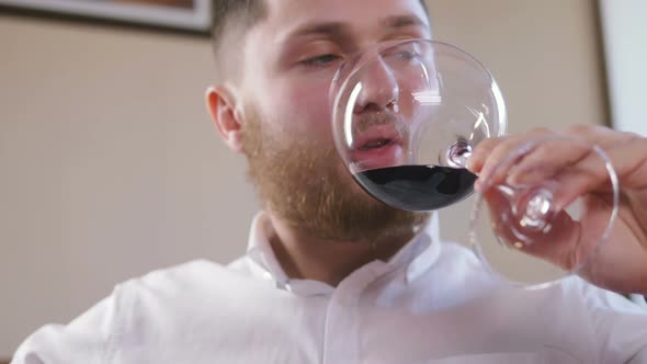 Young Man Drinking Wine From a Glass in Restaurant alt