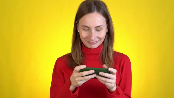 Gambling Young Woman Play Mobile Cell Phone Hold Gadget Smartphone Video Pc Games Isolated on Yellow alt