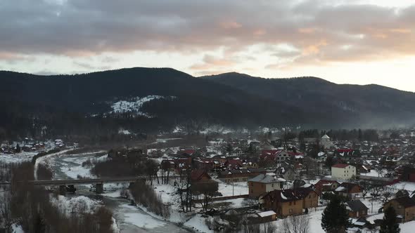 Aerial view of a Mountain Village with Hills Covered in Snow