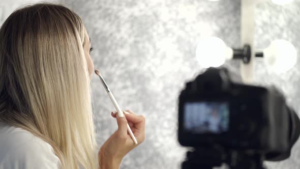 The Pretty Blond Makeup Artist Is Applying Eyeshadow Looking in a Mirror alt