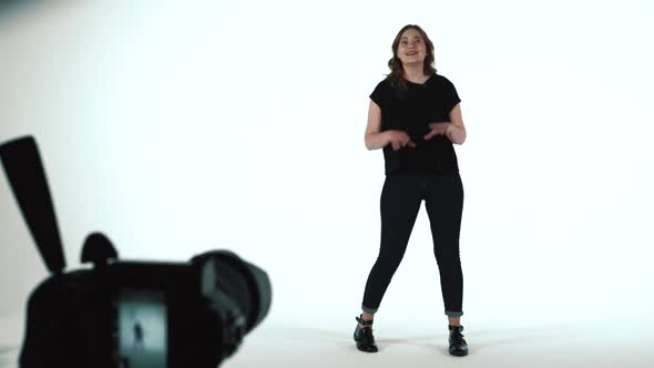 Young Woman Standing Near Camera While Explain Something in White Studio