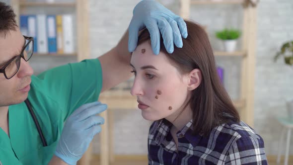 Doctor Examines a Young Woman with Large Moles on Her Face and Gives Recommendations Close Up alt