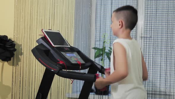 Young guy goes in for sports on a treadmill at home. Overall plan