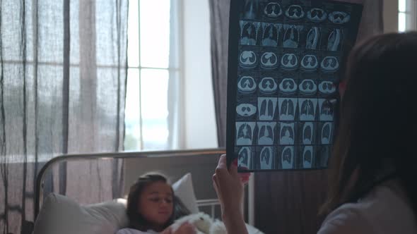 In a Hospital Room: Doctor Looks at MRI Scan of a Girl