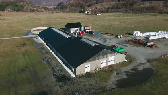 Dairy Barn, Silo, And Enclosure For Milk Production On Agricultural Landscape In Norway. aerial orbi alt