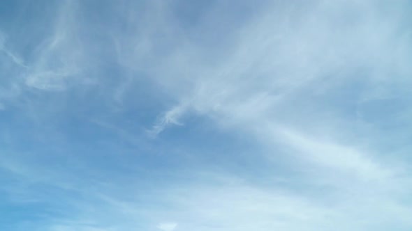 Light White Clouds Fly Across a Bright Blue Sky alt