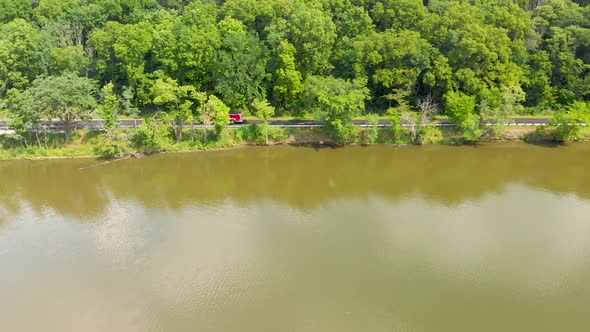 Drone right flight over a small country road in an Illinois forest preserve with lush green trees as alt