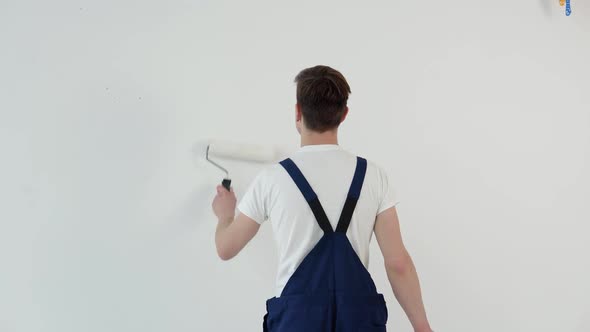Painter with a Roller in His Hands Paints a White Wall alt