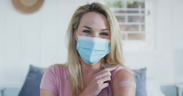 Happy caucasian mature woman showing plaster on arm where she was vaccinated against coronavirus alt
