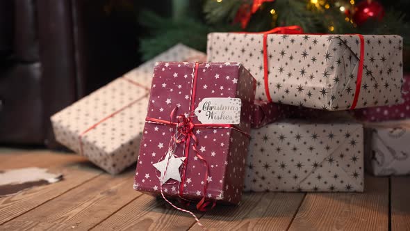 Christmas Beautiful Gift Boxes in a Stack of Presents Lie on the Wooden Floor Under the Tree alt