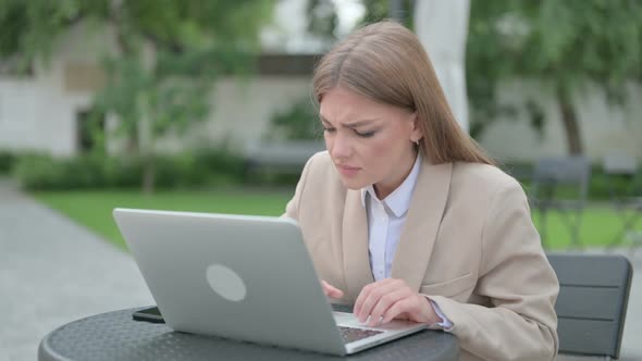 Young Businesswoman Feeling Angry Working on Laptop in Outdoor Cafe alt