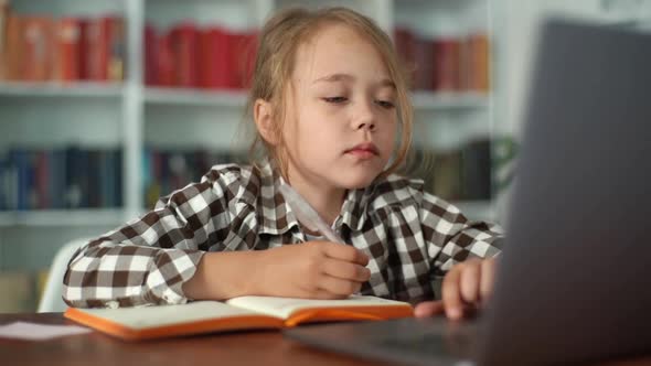 Closeup Portrait of Focused Primary Child School Girl Doing Homework Writing Notes in Paper Notebook alt