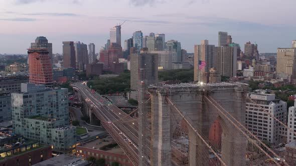 An aerial view of the Brooklyn Bridge at sunrise. The camera orbit the American flag on the bridge's alt