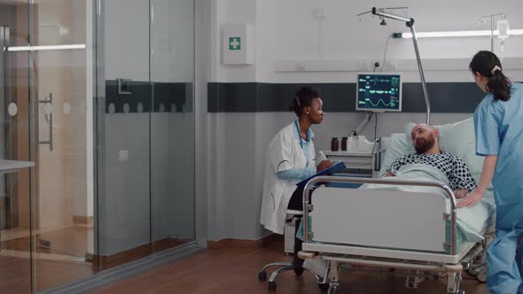 Afro American Practitioner Monitoring Sick Man Analyzing Sickness Symptom alt