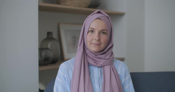 Looking at the Camera and Nodding Her Head, a Muslim Woman in a Hijab Is Talking on a Video Link and alt