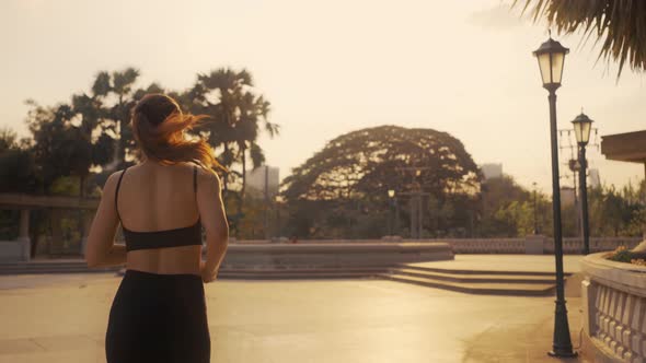 Woman in sportswear jogging exercise in the city at sunset.
