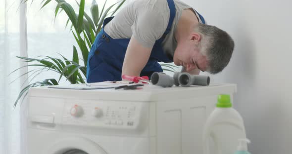 Plumber repairing a washing machine and customer watching
